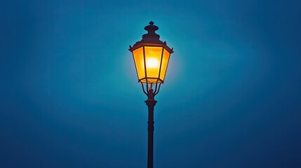 A vintage street lamp glowing warmly, standing alone against a peaceful, deep blue night sky.