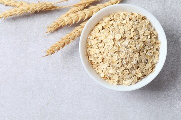 Composition with oatmeal flakes on gray background. Cooking breakfast