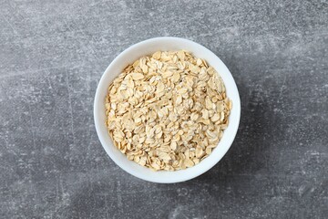 Composition with oatmeal flakes on gray background. Cooking breakfast