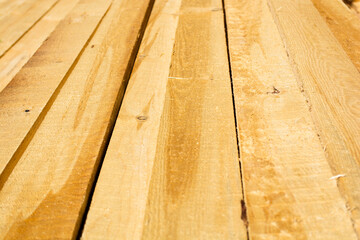 Wooden planks stacked in sawmill or carpentry shop. Sawing, drying and selling timber. Industrial background.