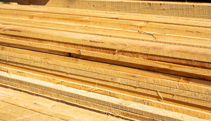 Wooden boards are stacked in a sawmill or carpentry shop. Sawing drying and marketing of wood. Industrial background.