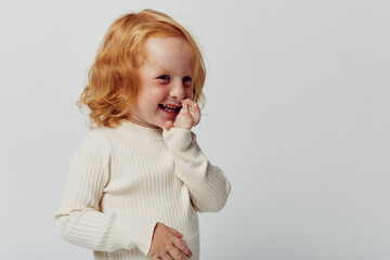 Redhaired girl with hands on face standing against white background in a beauty and fashion studio...