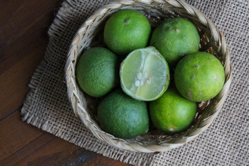 several whole limes and pieces in a bamboo basket	