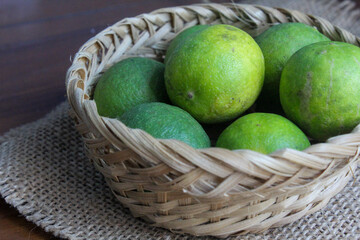 several whole limes and pieces in a bamboo basket	