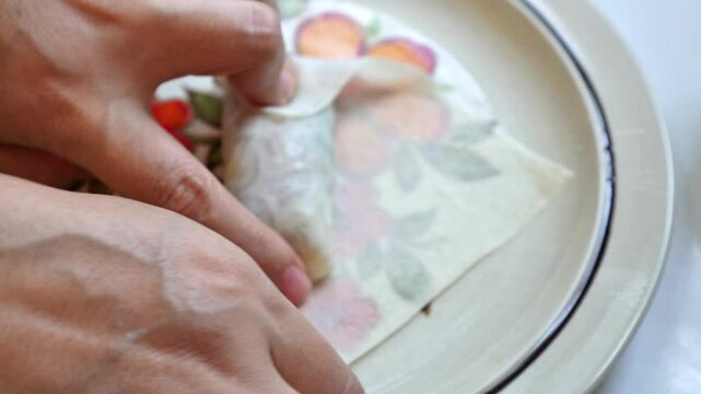 Video footage of a chef wrapping vegetarian spring rolls on a plate in a home kitchen.