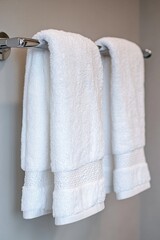 A pair of white towels hung on a wall in a clean and minimalist setting