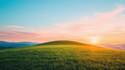 Naklejka premium A serene landscape featuring a grassy hill against a vibrant sunset sky, showcasing tranquil colors and natural beauty.