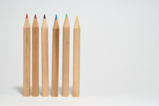 Lapices de madera formando una fila, lapices de colores en un fondo blanco.