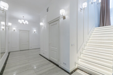 Well-lit hall of a private house with stairs. Neoclassical style in interior design.