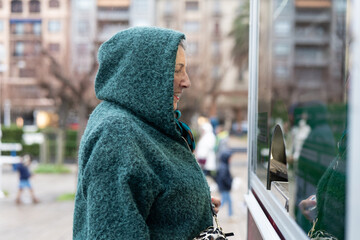 Senior woman at a ticket booth eagerly awaiting her turn for an afternoon adventure in a bustling...