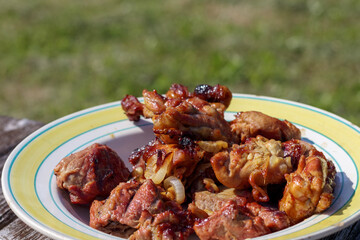 
a plate of tasty meat dish served on a wooden surface with green grass in the background.
