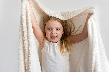 Chickenpox in a little child. Portrait of a little girl with a blanket on her head with a rash from...