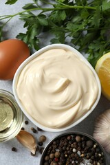 Bowl with mayonnaise and ingredients for cooking on gray background