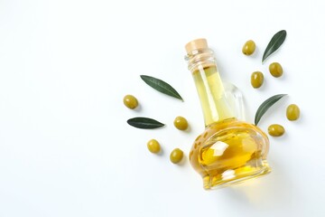 Bottle of fresh olive oil and olives with leaves on white background