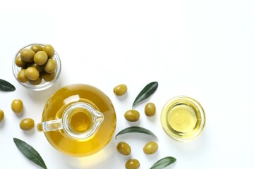 Bottle of fresh olive oil and olives with leaves on white background