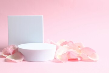 Pink rose petals with podium on a color background