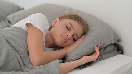 Tired Young Woman Sleeping while Lying on Side in Bed