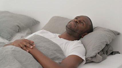 Pensive African Man Lying in Bed