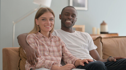 Smiling Interracial Couple Sitting at Home