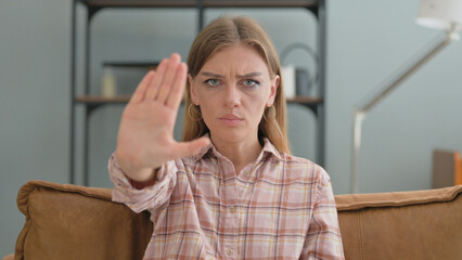 Stop Gesture by Young Woman Sitting on Sofa at Home