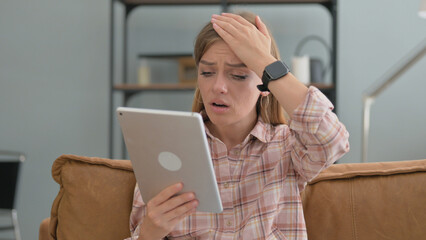 Young Woman with Loss on Tablet while Sitting on Sofa at Home