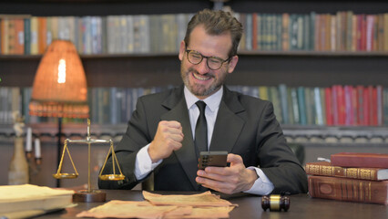 Middle Aged Lawyer Celebrating Success on Phone in Office