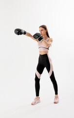 Fototapeta premium Woman practicing boxing technique in athletic gear against a neutral backdrop during a training session