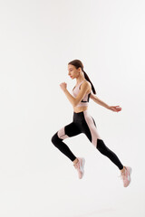 Young woman engaged in fitness activity demonstrating a dynamic running pose on a minimalist background