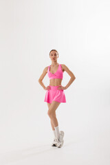 Model poses in bright pink athletic wear showcasing confidence and style in a minimalist setting
