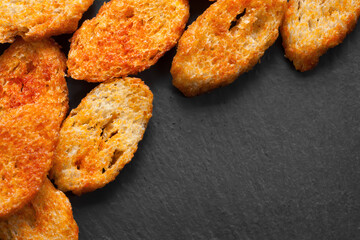 Rusks with spices. Fried croutons. Copy space. Croutons on a dark