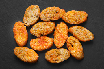 Rusks with spices. Fried toast. Top view. Croutons on a dark