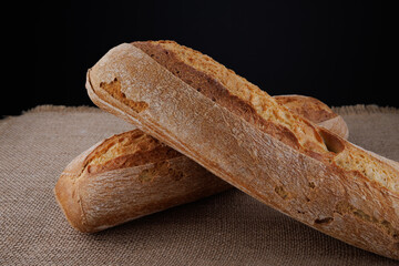Two loaves of baguette lie on a burlap napkin. Two crossed baguettes.