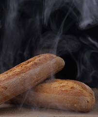 Baguette steaming on dark background. Fresh hot bread.