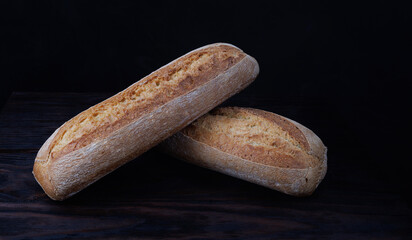 Baguette steaming on dark background. Fresh hot bread. Two loaves of baguette on black background.