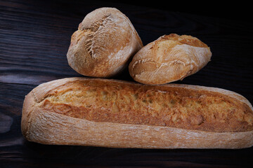Two beautiful baguettes on a dark wooden background. Sliced bread. Art bread.