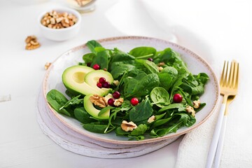 Fresh spinach salad with avocado and walnuts served on a rustic plate