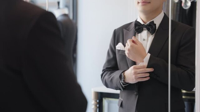 Close up young adult happy man asia people prepare clothes for tied knot wedding life event party get dressed up wear cuff link bow tie try on full male suit at fitting room modern luxury shirt store.