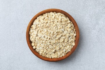 Composition with oatmeal flakes on gray background. Cooking breakfast