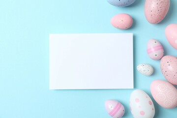 Happy Easter. Colorful eggs with white paper card on a pastel blue background, space for text or advertising