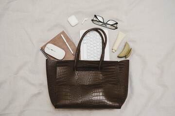 A stylish and chic brown tote bag that is filled with all the essential items you need for work and...