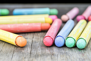 Naklejka premium Old chalks scattered on a wooden school board