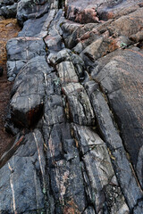 A detailed close-up of a rugged rock formation showcasing intricate geological layers, fissures, and mineral veins.