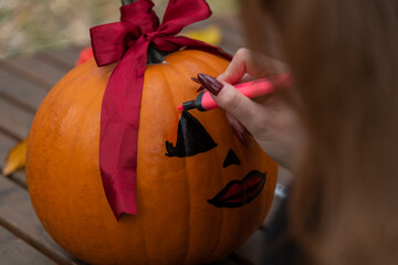 Woman decorating a pumpkin with face details for Halloween celebration