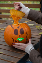 Woman carving a pumpkin with Halloween decorations outdoors in autumn