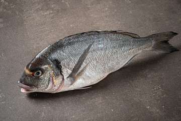Freshly Caught Fish Resting on Dark Stone Surface, Highlighting Its Intricate Scales and Vibrant Eyes in a Culinary Preparation Setting