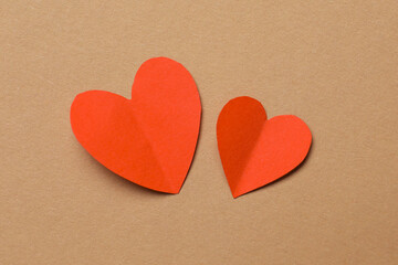 Fototapeta premium Valentine's Day. Paper hearts on brown background, top view