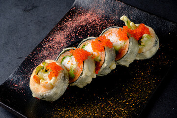 Delightful Fried Sushi Rolls Adorned With Vibrant Toppings Placed Elegantly on a Sleek Dark Platter During an Intimate Dining Experience