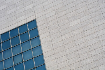 A part of a building with large glass windows set into a wall covered with stone slabs
