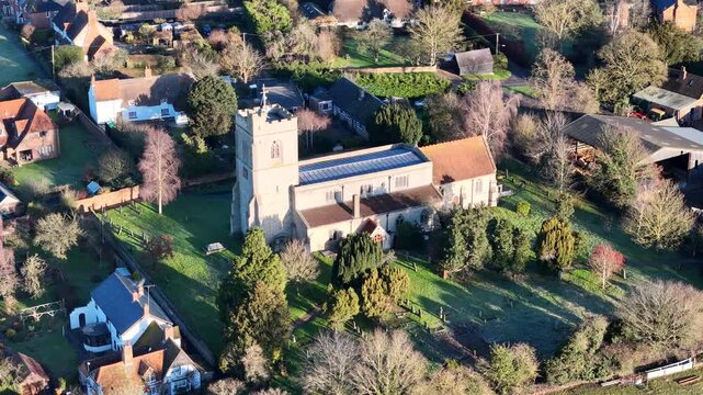 Drone footage of St Mary's church in Hardwick village surrounded by houses and lush greens