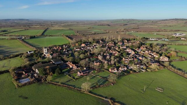 Drone footage of Hardwick village surrounded by green countryside fields on a sunny day